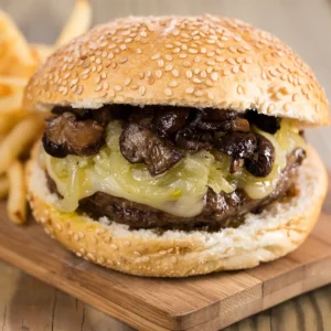 Close-up of a juicy burger from Wise Guys Pizzeria, featuring sesame seed bun, melted cheese, sautéed mushrooms