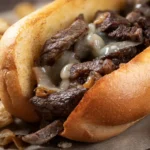 Close-up of a Philly cheesesteak sandwich from Wise Guys Pizzeria, featuring tender steak, melted cheese, and soft